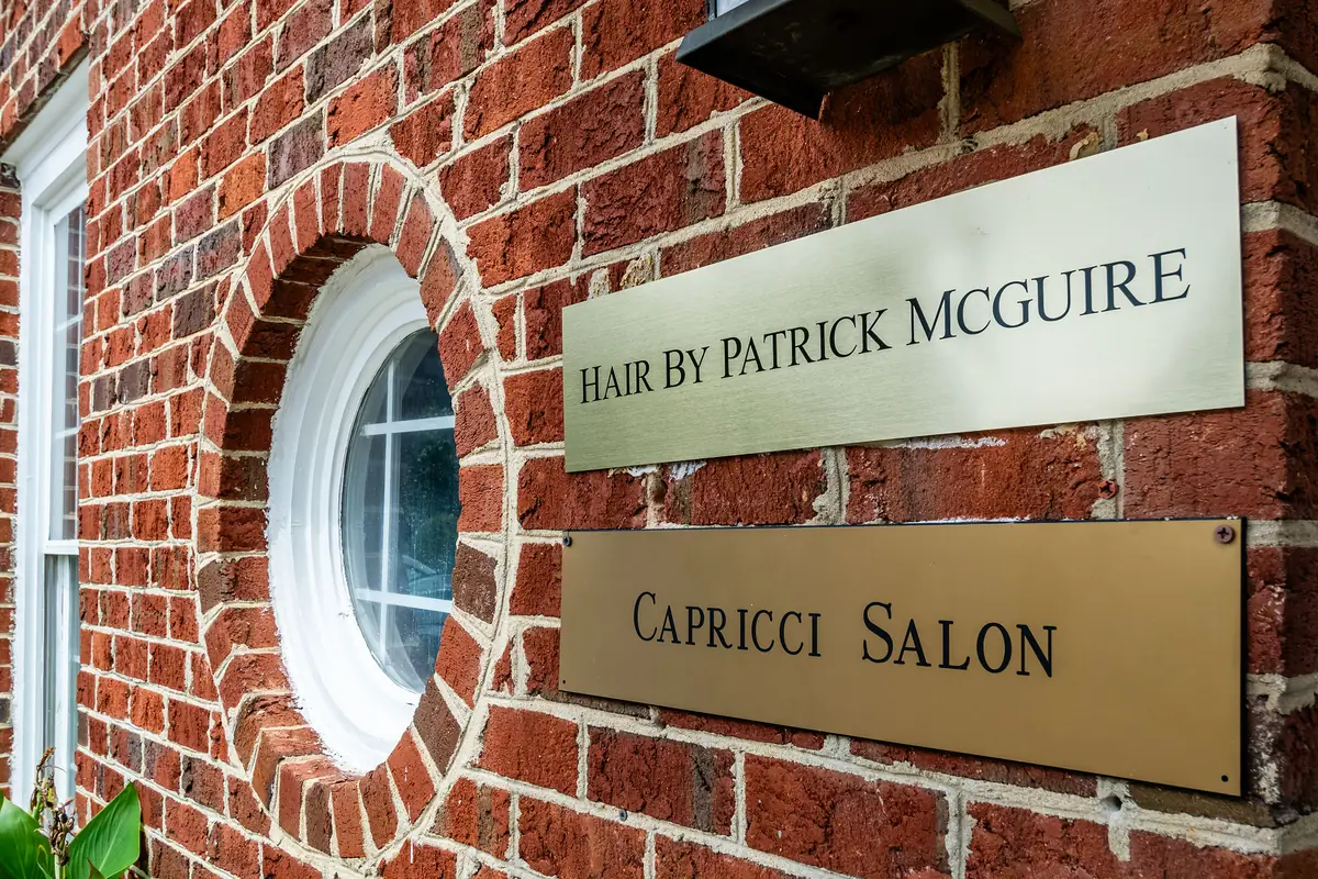The brass plaque beside the round window reading Hair by Patrick McGuire.